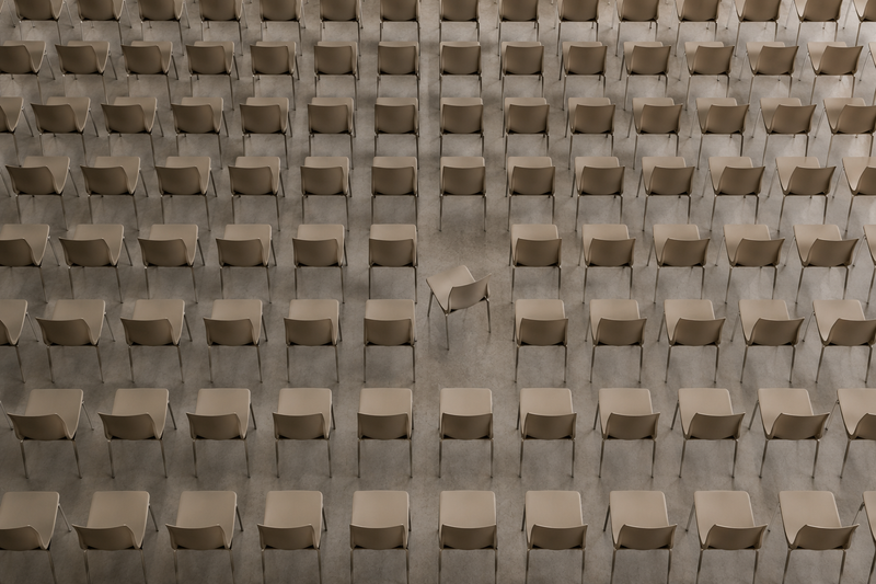 Rows of identical chairs with one chair subtly turned, illustrating how small visual differences immediately draw attention and shape perception.