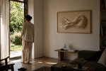Woman in a living room with ODE artwork LOVE, contemporary wall art inspired by connection and human experience.